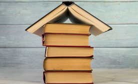 House structure made with vintage books against wooden wall