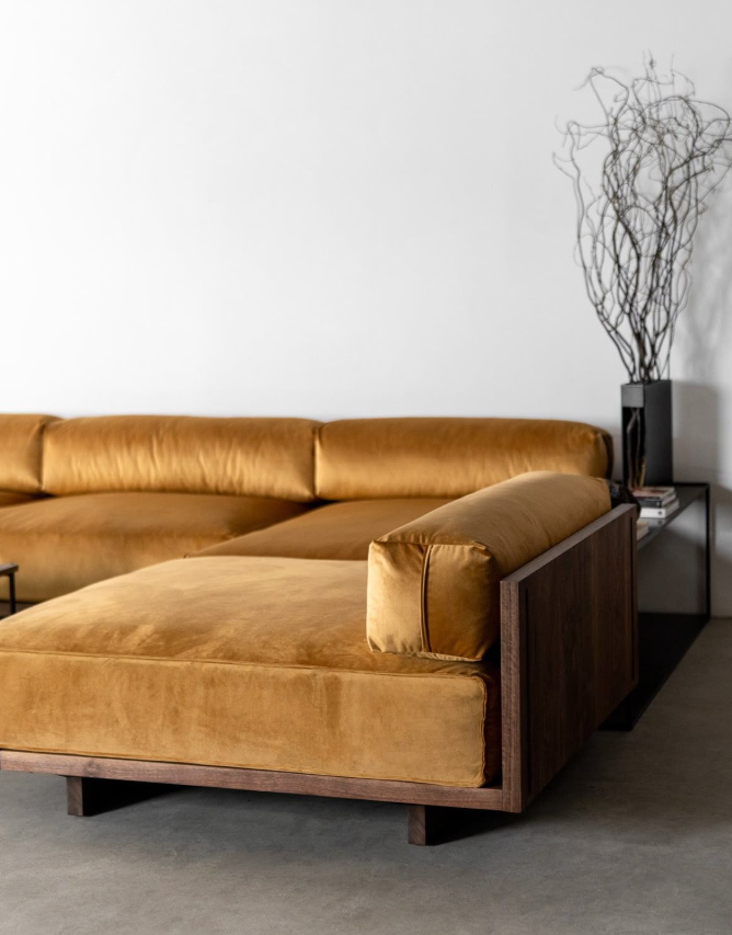 μουσταρδί βελούδινος καναπές δίπλα σε αποξηραμένο φυτό