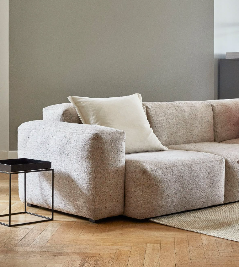 μπεζ μίνιμαλ καναπές δίπλα από μαύρο μεταλλικό βοηθητικό τραπέζι