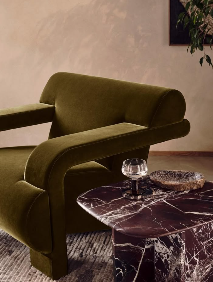 βελούδινη πολυθρόνα σε πράσινο λαδί δίπλα σε μαρμάρινο coffee table